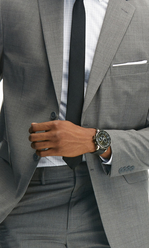 Close up of a man wearing a State of Matter grey suit with a black tie and sustainable white button down.