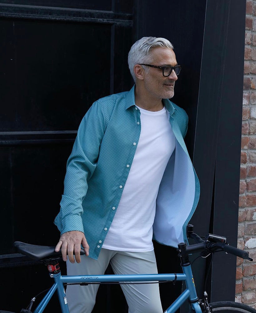 A man in glasses with a blue bicycle wearing an open State of Matter Sustainable Men's Sage Circle Long Sleeve Dress Shirt