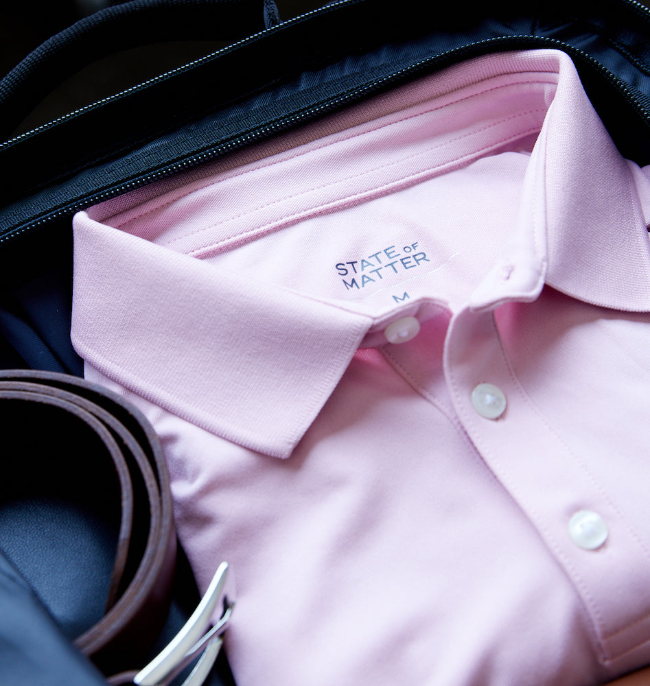Image of a rolled up belt and folded State of Matter Sustainable Men's Cameo Pink Polo Shirt Classic Fit in a suitcase 