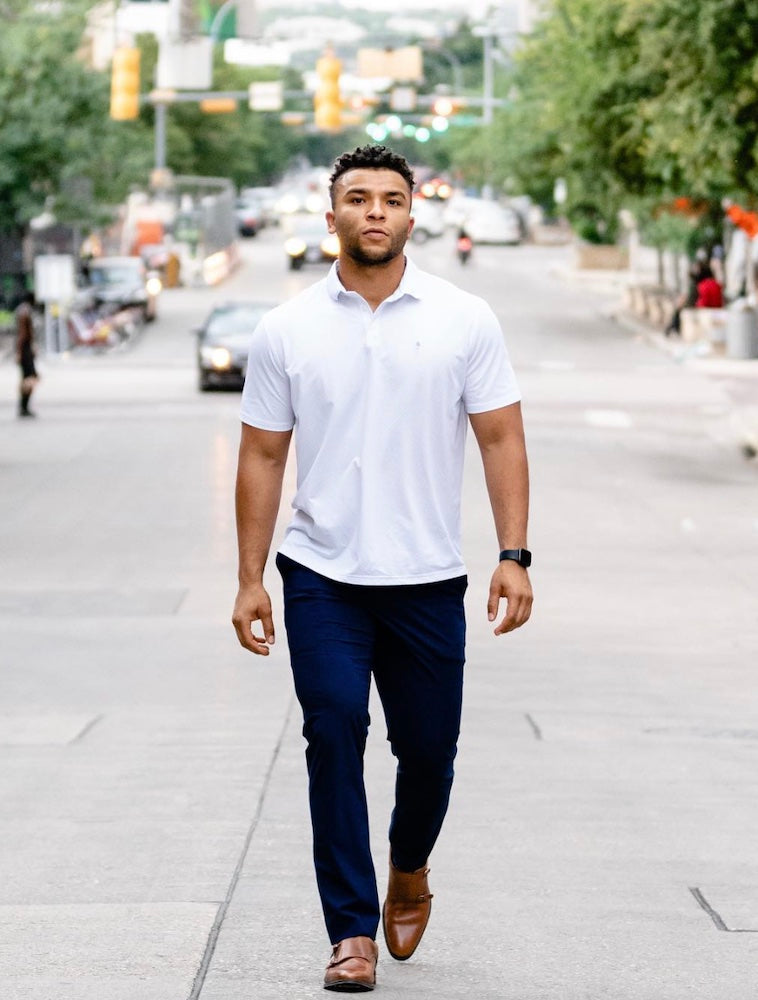 A walking in the middle of the road in a State of Matter Sustainable Men's White Polo Shirt and business casual pants in Deep Navy