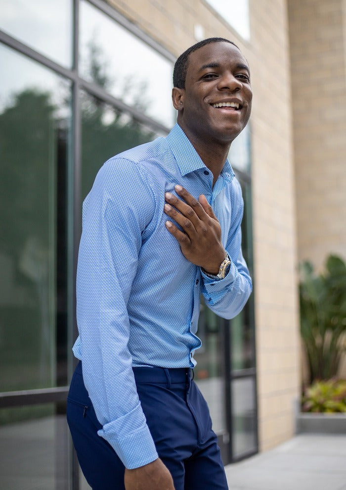 A man laughing with his hand on his chest is wearing a State of Matter blue button-up shirt with arrow pattern and Sustainable Navy Blue Men's Joggers. 