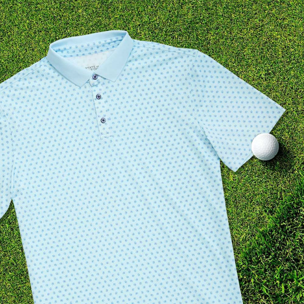 A State of Matter Men's Baby Blue Polo Shirt laid out on grass next to a golf ball