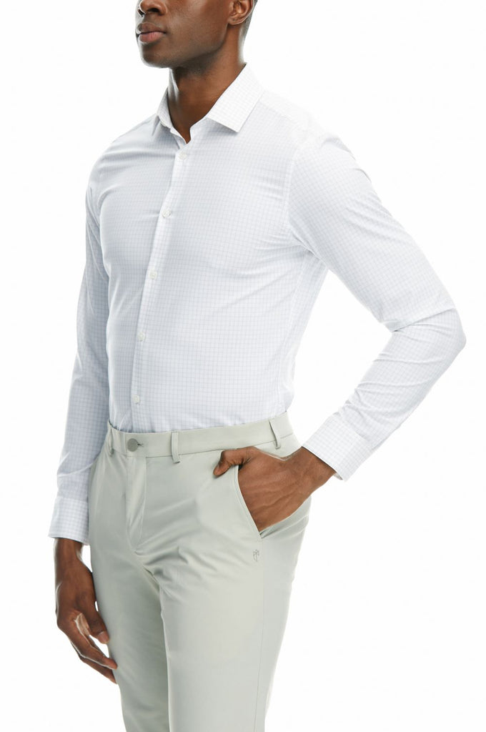 Side picture of a man wearing State of matter sustainable long sleeve grey checkered button down shirt and Gray chino pants with his hands tucked in the pockets